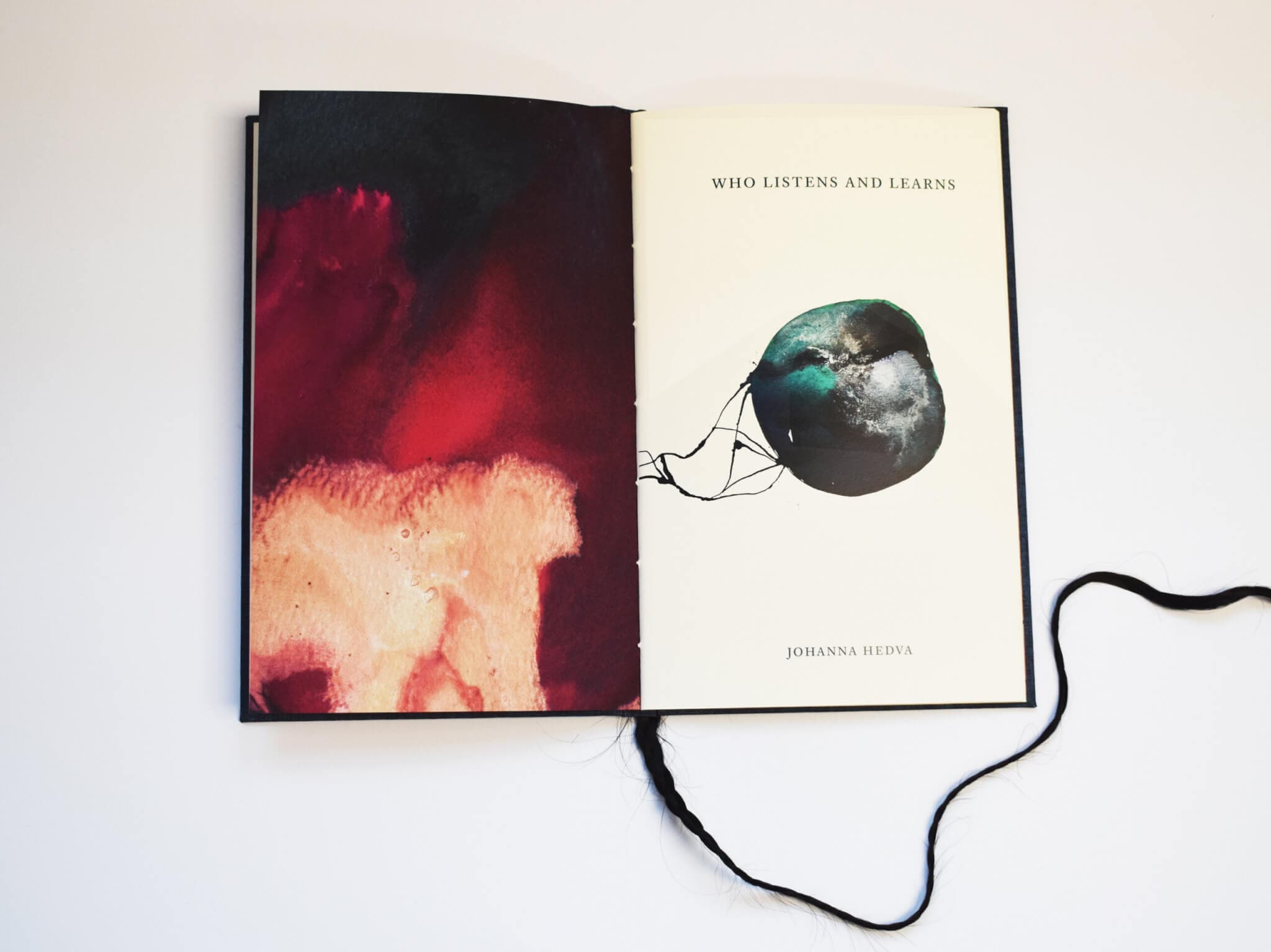 An open book displays a message, "Who Listens and Learns," while a black tassel appears from the bottom of the work.